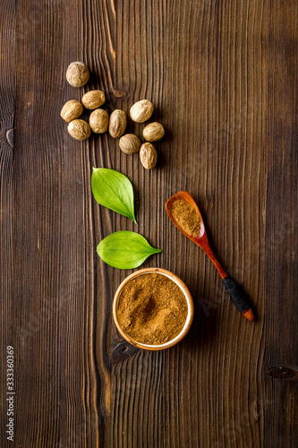 Nutmeg - ground indian condiment in spoon - on wooden background top-down