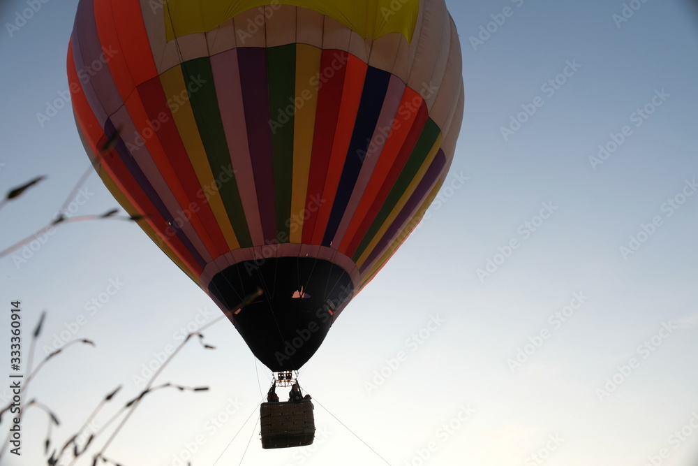 Fototapeta premium A balloon with a large wicker basket and passengers rises into the sky