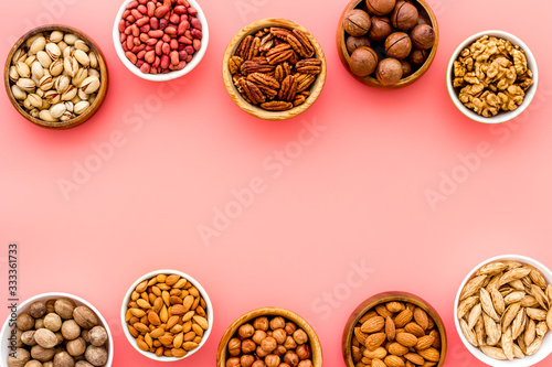 Nuts set in bowls on pink background top-down frame copy space mockup