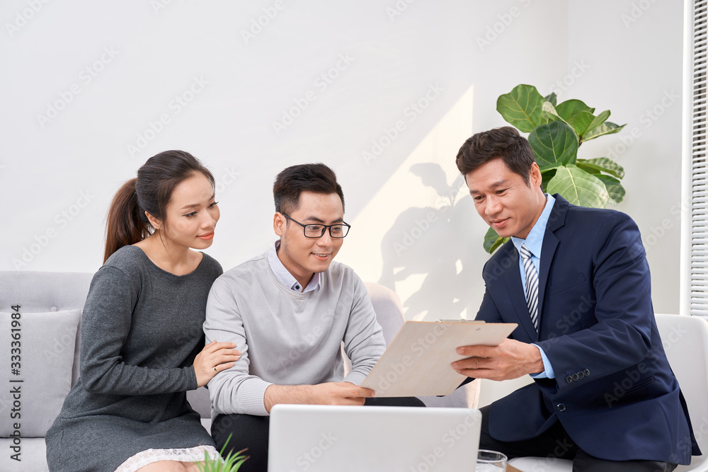 Sales Consultant showing new investment plans to young asian couple - obrazy, fototapety, plakaty 
