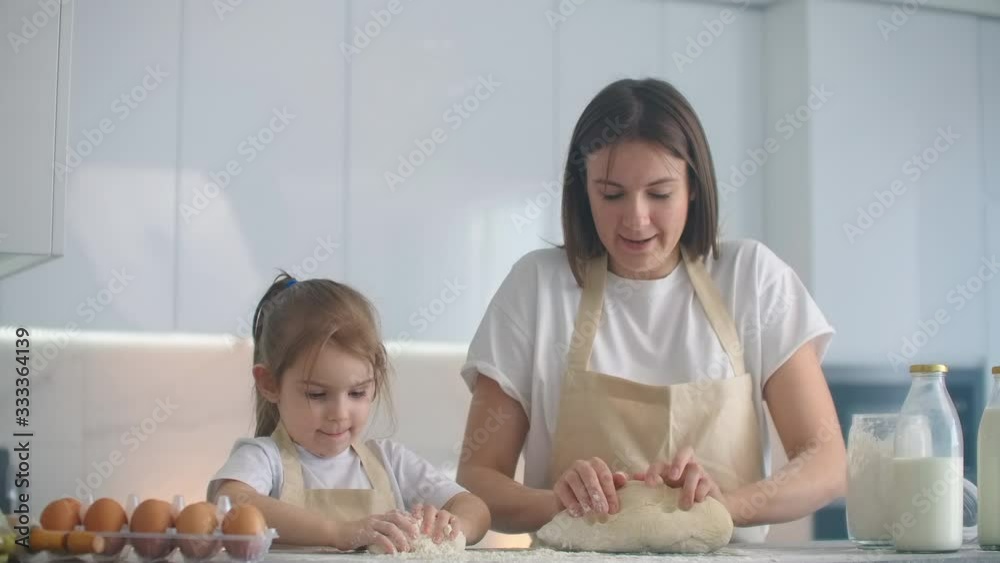 Mother and daughter cooking with dough mold in kitchen. Mother and daughter holding heart-shaped dough mold. Sculpt the dough with your hands to make blanks for pizza or pie, cookies Mother and daughter cooking with dough mold in kitchen. Mother and daughter holding heart-shaped dough mold. Sculpt the dough with your hands to make blanks for pizza or pie, cookies