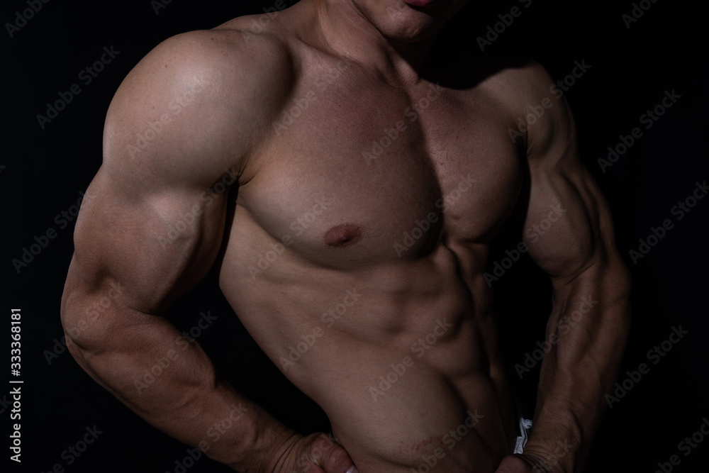 Muscular man showing muscles isolated on the black background. Concept of bodybuilding and creating your body at gym Muscular man showing muscles isolated on the black background. Concept of bodybuilding and creating your body at gym