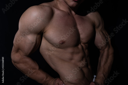 Muscular man showing muscles isolated on the black background. Concept of bodybuilding and creating your body at gym 