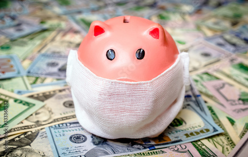 piggy bank in a mask on a background of american currency.The concept of coronavrius epidemic photo