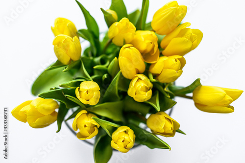 A bouquet of yellow Tulips in a glass vase on a white background. The view from the top. Copy space