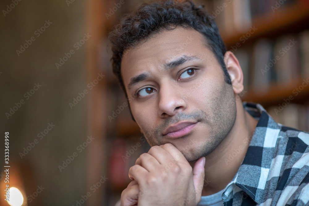 Dark-haired man in a checkered shirt looking serious Dark-haired man in a checkered shirt looking serious