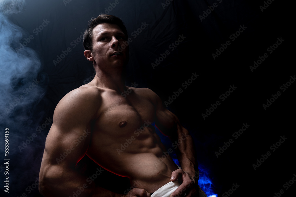 Muscular man showing muscles isolated on the black background. Concept of goal, afford, creation your self, perseverance, fortitude, focus and labor
