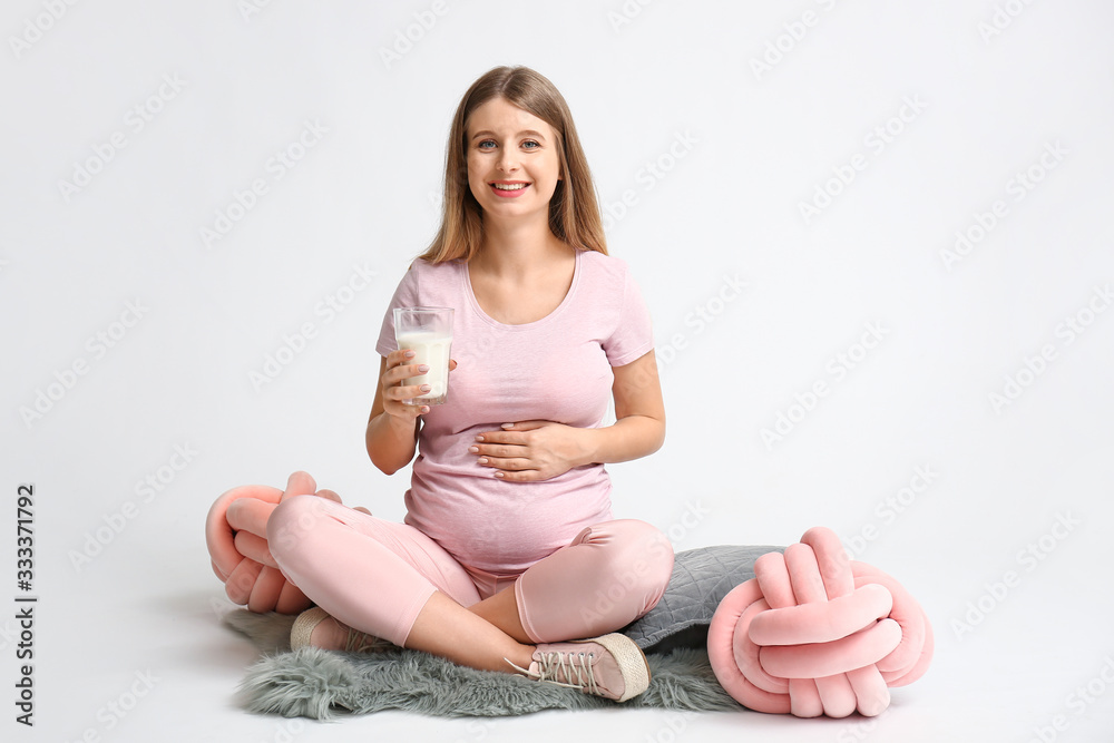Beautiful pregnant woman with milk on light background Beautiful pregnant woman with milk on light background
