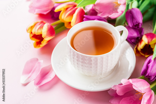 A cup of tea with tulips on rose background