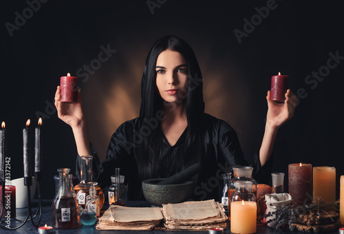 Female alchemist making potion on dark background photo