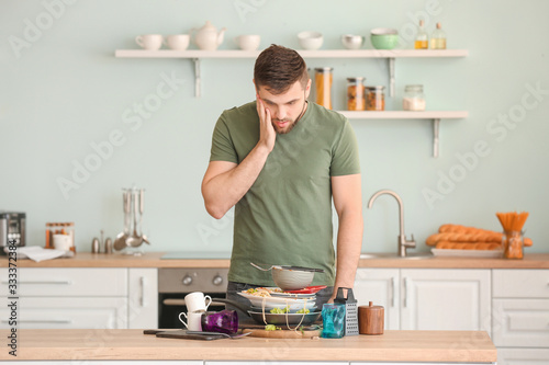 Shocked man looking at pile of dirty dishes on kitchen table