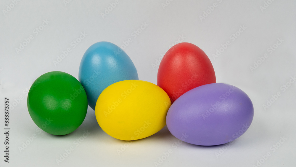 Easter eggs in many colors on a white background. Green eggs, blue eggs, yellow eggs, red eggs, purple eggs. Easter eggs in many colors on a white background. Green eggs, blue eggs, yellow eggs, red eggs, purple eggs.