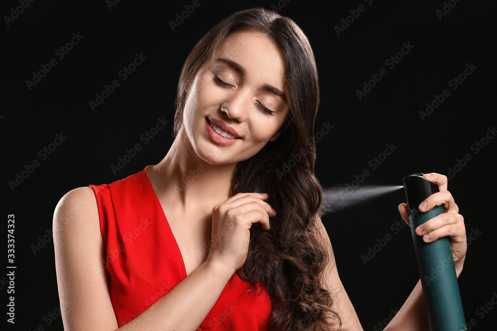 Beautiful young woman with hair spray on dark background Beautiful young woman with hair spray on dark background