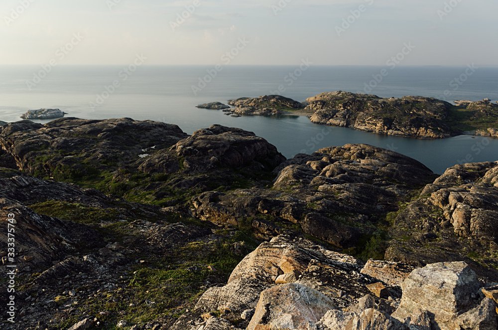 Summer contrast norway landscape, sunset - granite high shore and quiet Arctic Ocean in sunny weather.