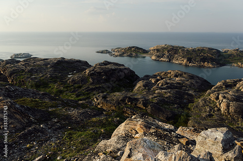 Summer contrast norway landscape, sunset - granite high shore and quiet Arctic Ocean in sunny weather.