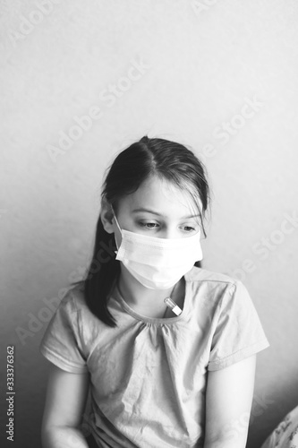  Sad girl in mask in bed in quarantine.