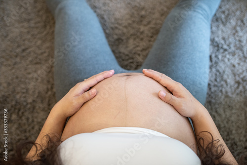 Pregnant woman feeling happy at home while taking care of her child.