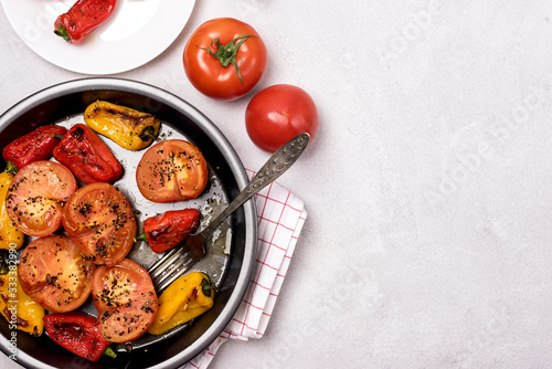 Big Black Plate and Small White Plate of Grilled Vegetables on Light Background Baked Tomatoes and Peppers Tasty Healthy Diet Dinner or Lunch Copy Space