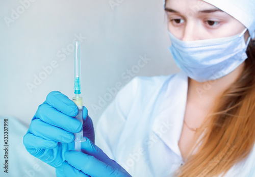 A nurse in rubber gloves holds a syringe. A single-use syringe containing the vaccine. Sterility.
