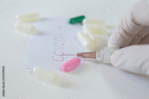 Red Covid-19 letter is placed between needle and capsule on white background. Antibiotics Health care concept  viral vaccine. Concept prevent spread