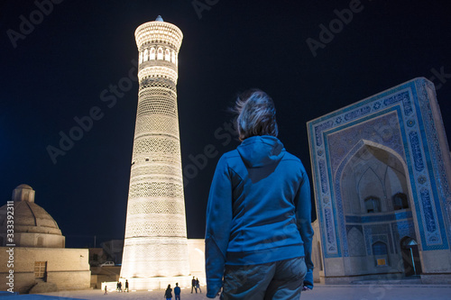 A tourist (girl) in front of Great Minaret of the Kalon and Kalon (Kallan) Mosque. Bukhara, Uzbekistan, Central Asia. photo