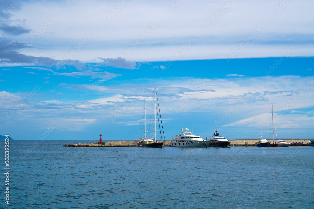 Wide panoramic view of luxury yachts and sailing boats moored in harbor of Santa Margherita Ligure, Italian Riviera. Beautiful mediterranean landscape with cloudy blue sky.