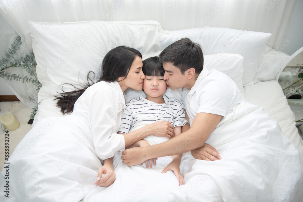 Young asian mother, father and boy sleeping in bed, mom and dad kiss on cheek of son,view from above Young asian mother, father and boy sleeping in bed, mom and dad kiss on cheek of son,view from above