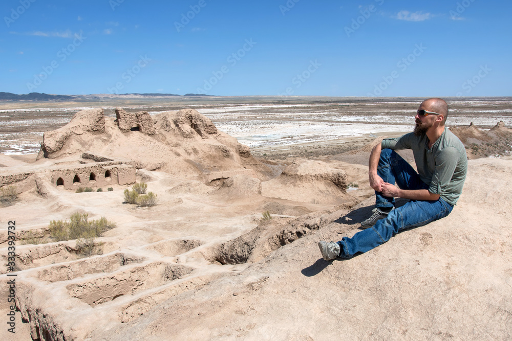 Naklejka premium European tourist in Toprak-Kala fortress (ancient Capital of Khorezm, one of the most popular touristic attraction in the country). Karakalpakstan, Uzbekistan, Central Asia.