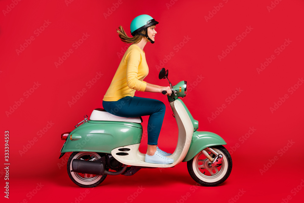 Profile side view of her she nice attractive lovely cheerful cheery girl driving moped to college high school motion adventure isolated on bright vivid shine vibrant red color background Profile side view of her she nice attractive lovely cheerful cheery girl driving moped to college high school motion adventure isolated on bright vivid shine vibrant red color background