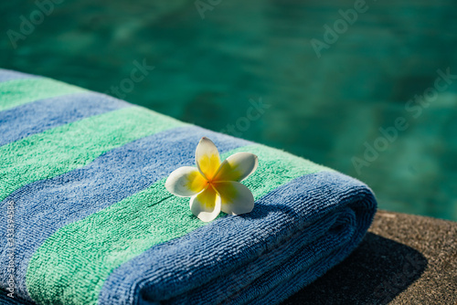 Blue towel and franjipani flower near swimming pool