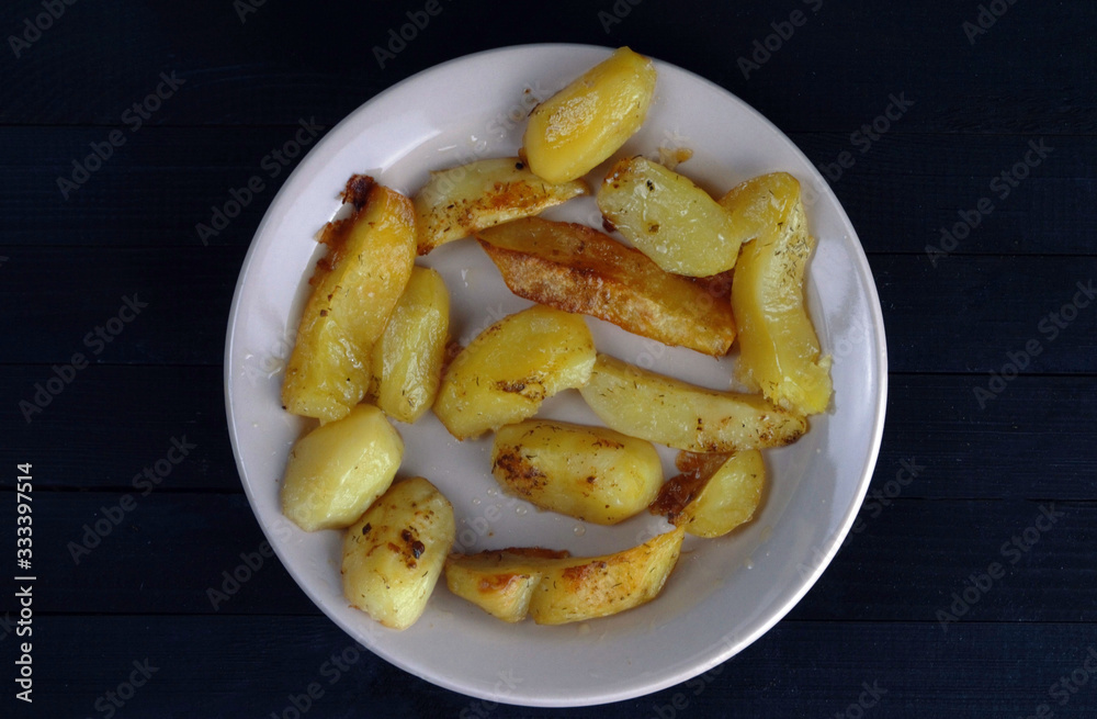  rustic potato lies on a plate on a black background