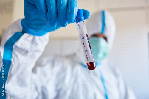 Researchers in protective clothing with Covid-19 blood sample