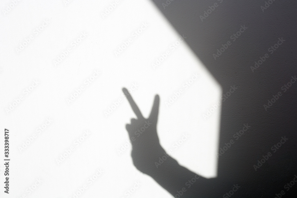 silhouette shadow hand doing peace sign on white wall, isolated home silhouette shadow hand doing peace sign on white wall, isolated home
