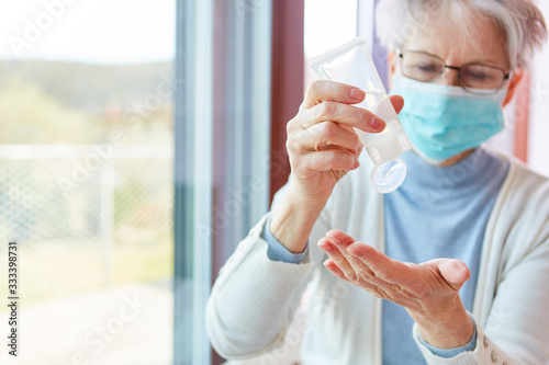 Senior woman in quarantine disinfecting hands