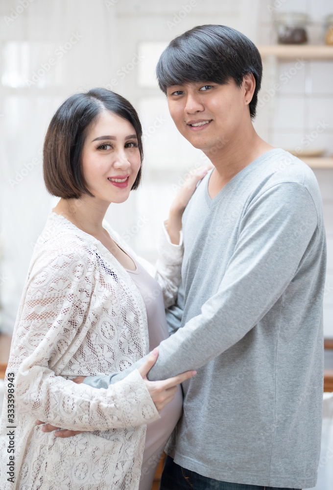 Closed up Asian man and pregnancy woman stand and hug in kitchen at home. Love and care of pregnant mother’s day concept Closed up Asian man and pregnancy woman stand and hug in kitchen at home. Love and care of pregnant mother’s day concept