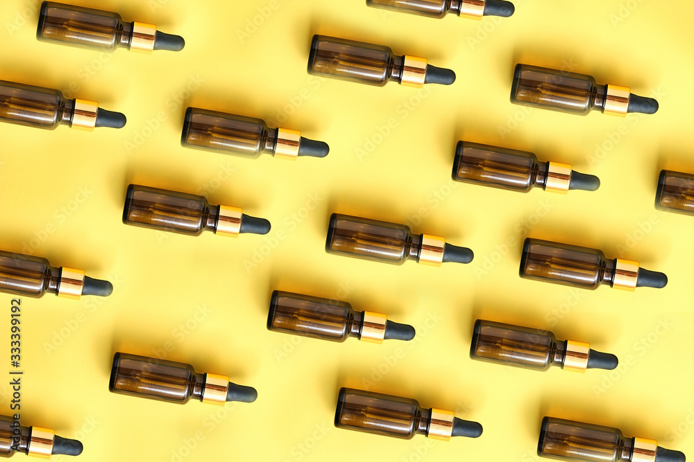 Flat lay pattern of natural cosmetics from small glass oil bottles. Jars with organic essential on yellow background Flat lay pattern of natural cosmetics from small glass oil bottles. Jars with organic essential on yellow background