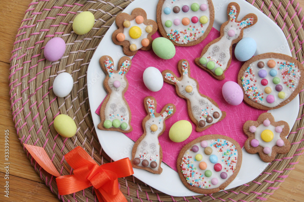Homemade Easter cookies in shape of bunny and Easter eggs on a plate on wooden table. Springtime background