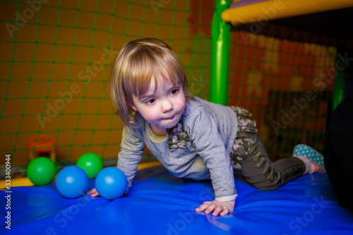 little girl 2 years old plays in a children's area with attractions