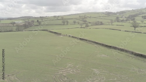 Aerial view flying above Welsh agricultural farmland meadow boundaries rising left dolly photo