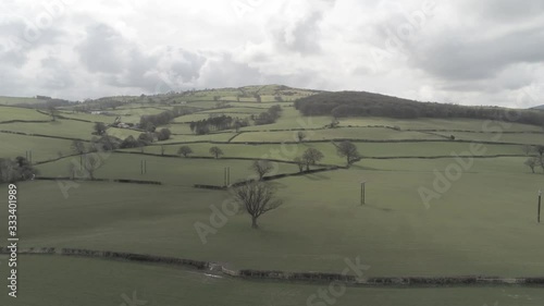 Aerial view flying above Welsh agricultural farmland meadow boundaries slow dolly right photo