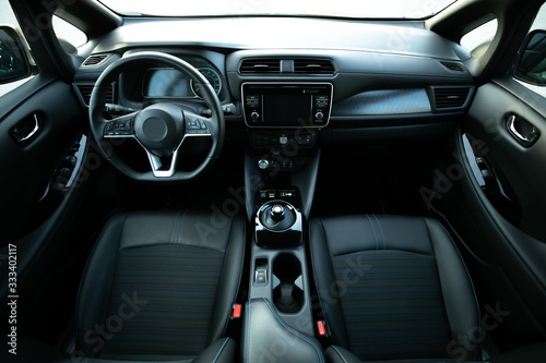 Electric car interior details of door handle with windows controls and adjustments. Inside car interior with front seats, driver and passenger, textile, windows, door panels, console
