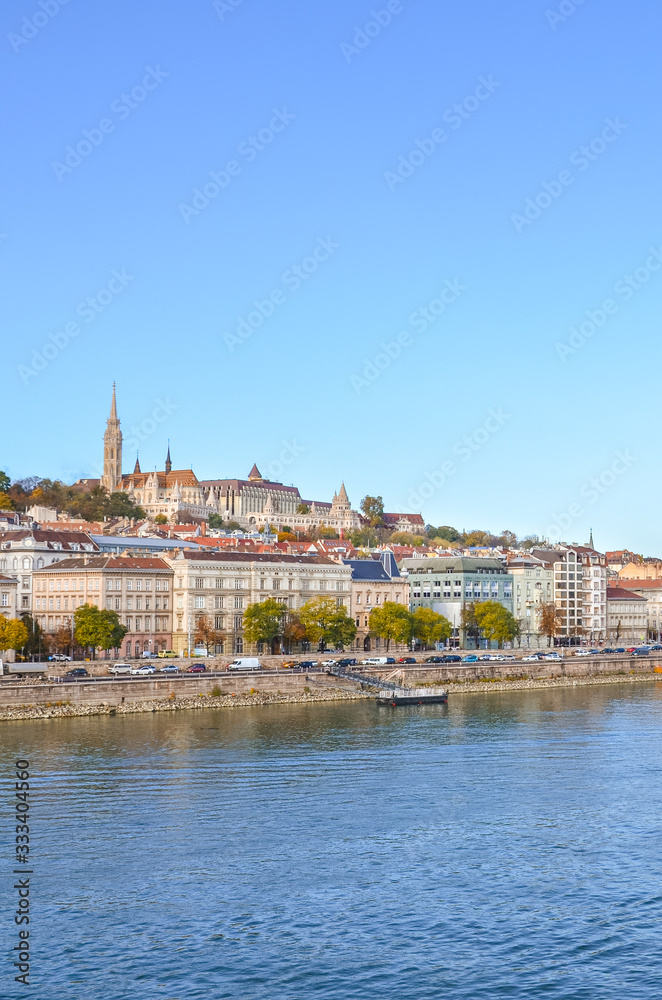 Beautiful cityscape of Budapest, Hungary. Matthias Church, Fishermans Bastion and the historical center in the far background. Waters of the Danube river in the foreground. Vertical photo