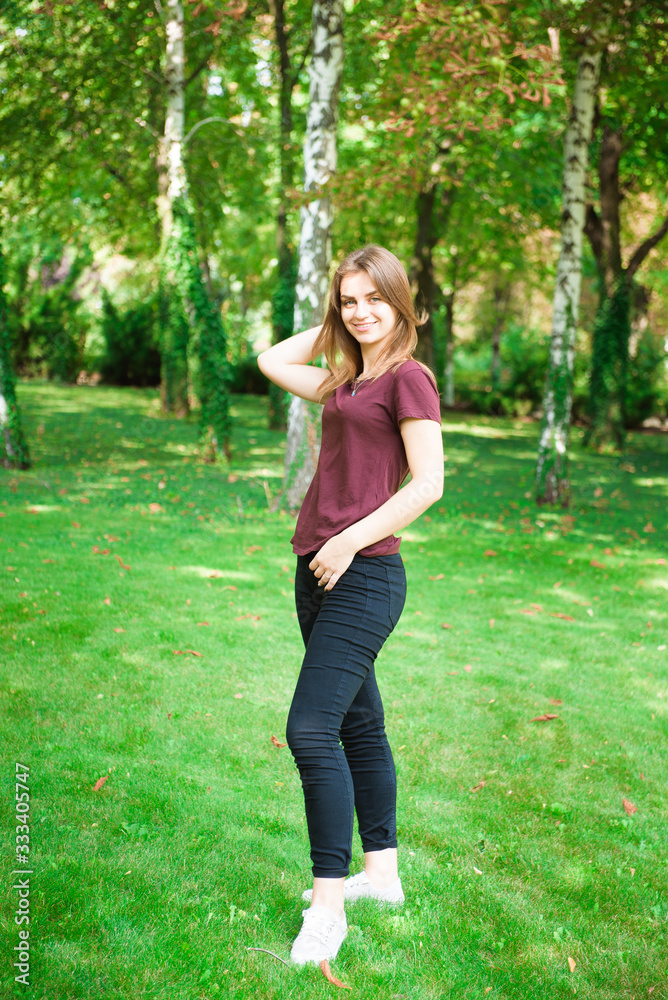 Positive woman with charming smile looks into camera. Girl posing on street in spring Positive woman with charming smile looks into camera. Girl posing on street in spring