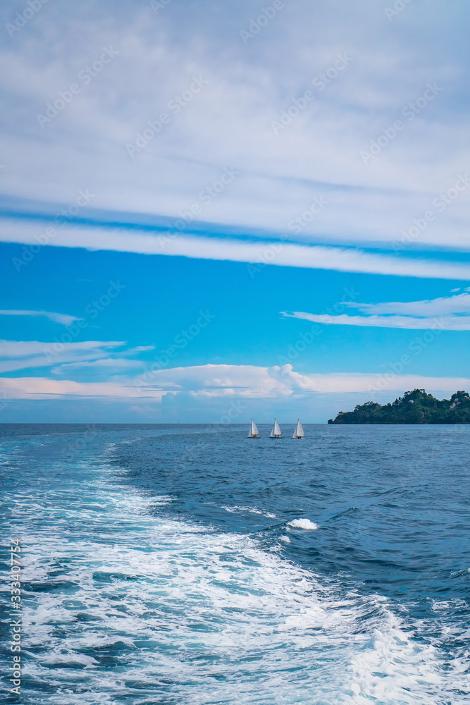 Obraz premium Beautiful scenic view of three white boats sailing in the open sea near the shore of Portofino, Italy.