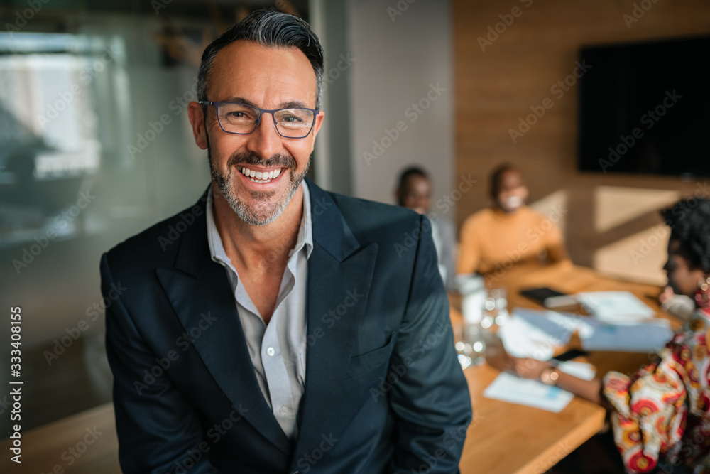 Portrait of smiling handsome businessman, with african coworkers workers hold a meeting in background Portrait of smiling handsome businessman, with african coworkers workers hold a meeting in background