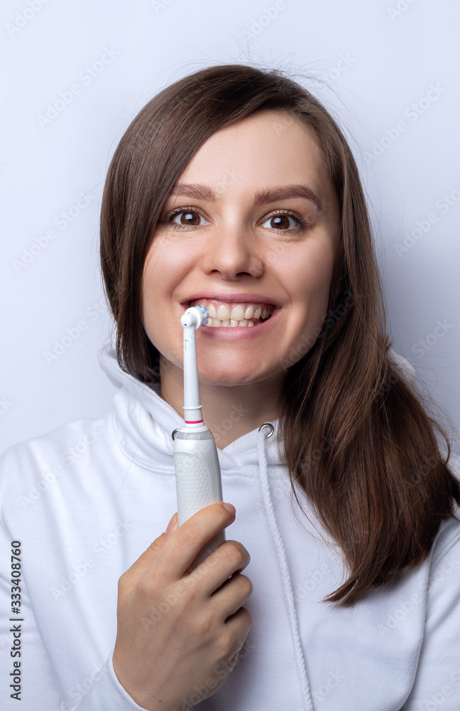 Young girl with beautiful teeth holds an electric toothbrush Young girl with beautiful teeth holds an electric toothbrush