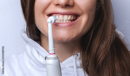 Close up of perfect and healthy teeth with electric toothbrush photo