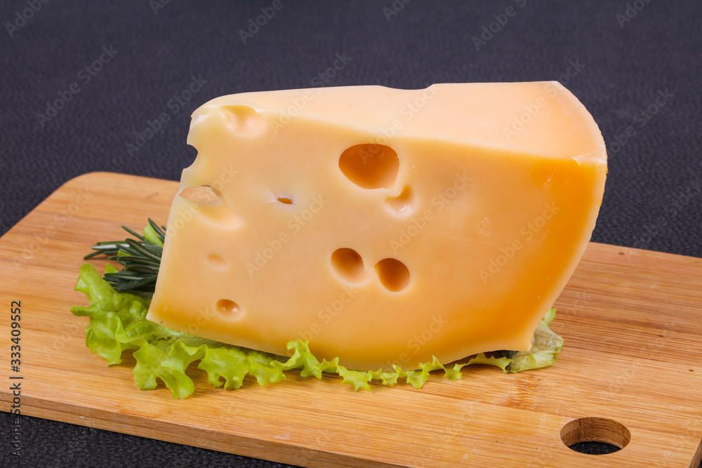 Maasdam cheese in the board served salad leaves Maasdam cheese in the board served salad leaves