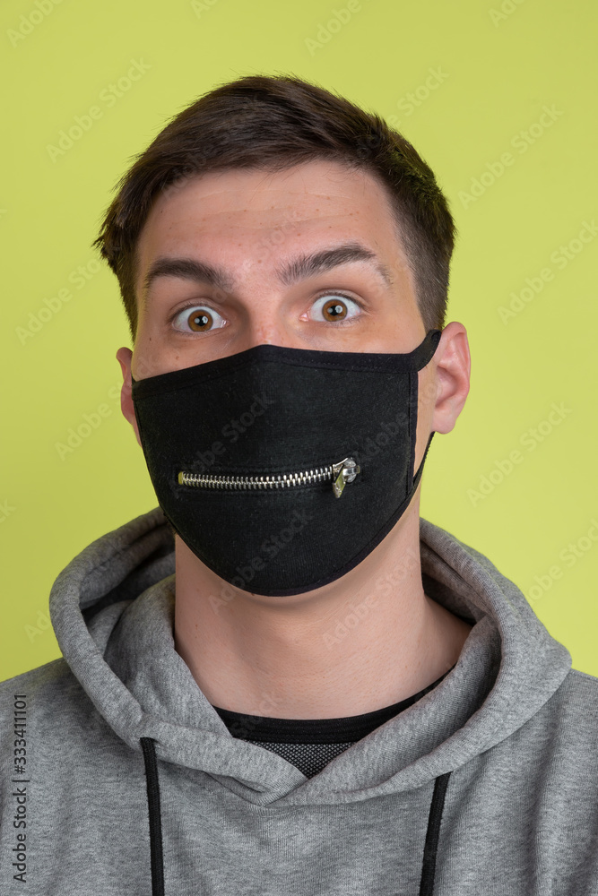 Astonished eyes. Caucasian man's portrait isolated on yellow studio background. Freaky male model in black face mask. Concept of human emotions, facial expression, sales, ad. Unusual appearance. Astonished eyes. Caucasian man's portrait isolated on yellow studio background. Freaky male model in black face mask. Concept of human emotions, facial expression, sales, ad. Unusual appearance.