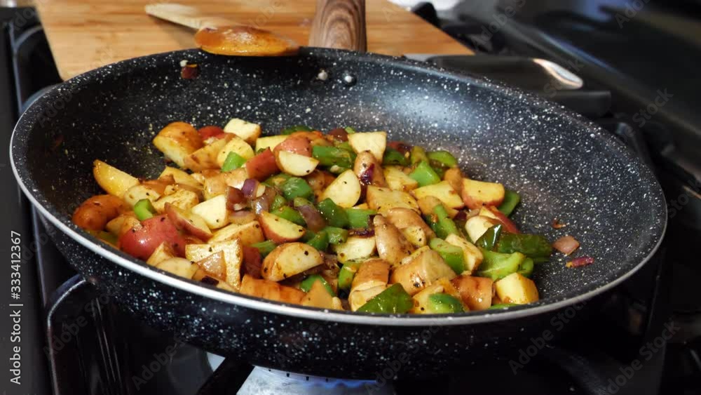 Mixed vegetable and potatoes cooking in frying pan at home, closeup Mixed vegetable and potatoes cooking in frying pan at home, closeup